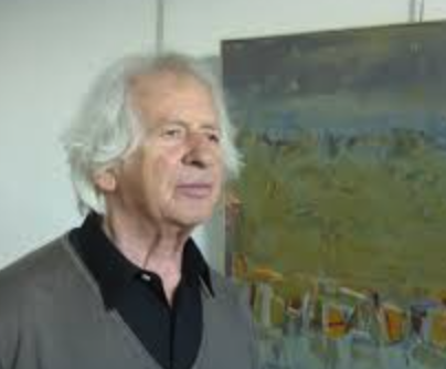 A portrait of an older man with white hair standing in front of an abstract painting.