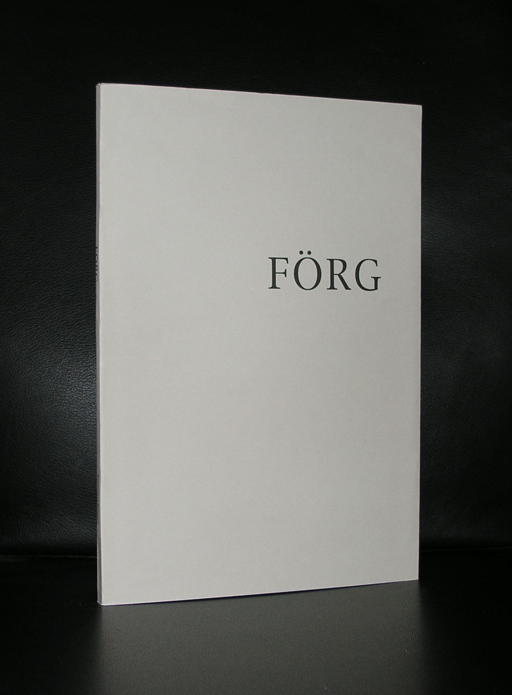 A minimalist art book featuring the title 'FÖRG' on a plain white cover, displayed against a black background.