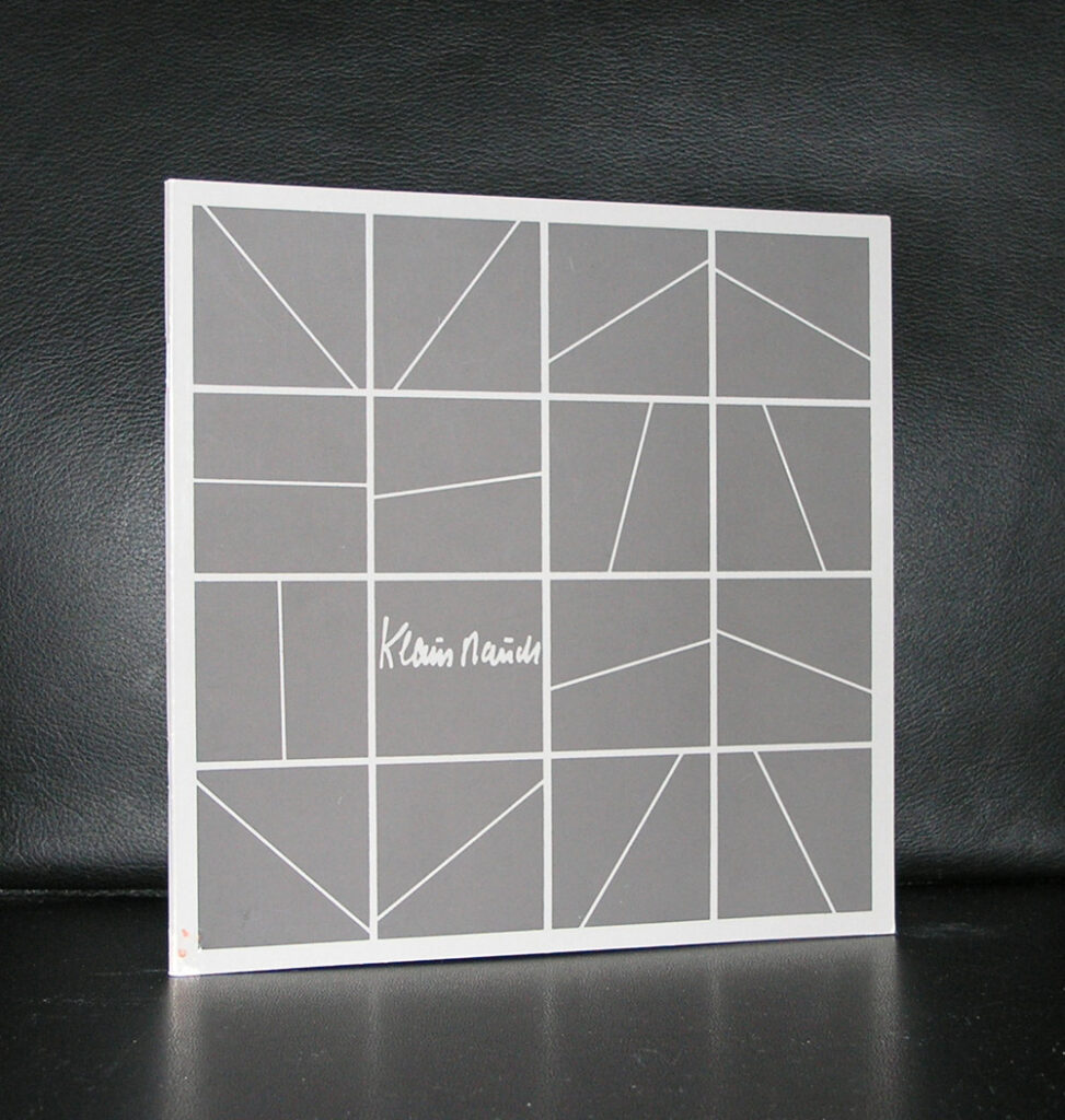 A book cover featuring a grid of geometric shapes in various muted tones, with a signature that reads 'Klaus Staudt'.