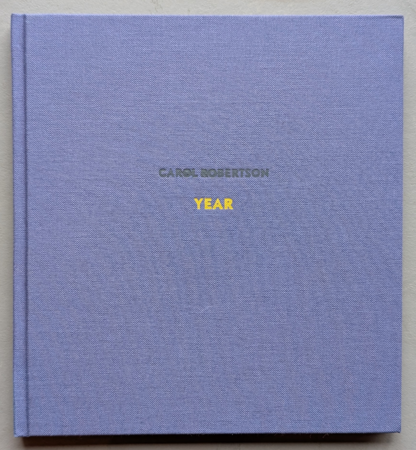 A hardcover art book titled 'YEAR' by Carol Robertson, featuring a purple cover with the author's name embossed in gray and the title in yellow.